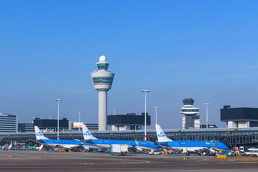 Airplanes at Amsterdam Schiphol airport in Holland. The planes are parked at the gates or taxxiing towards the runways around the terminal building.