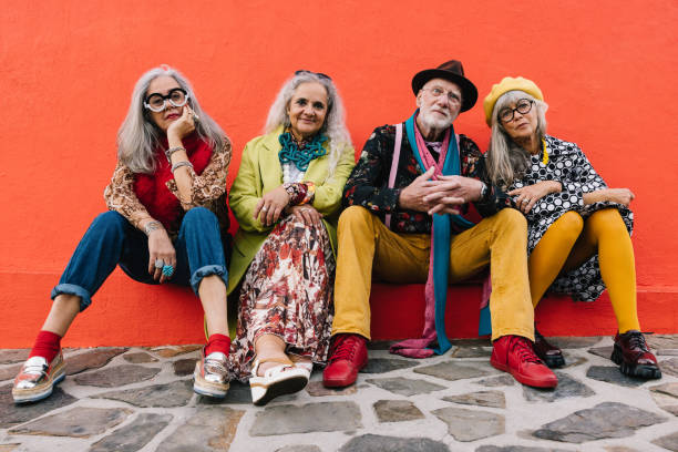istock Carefree elderly friends sitting against a red wall 1369301157