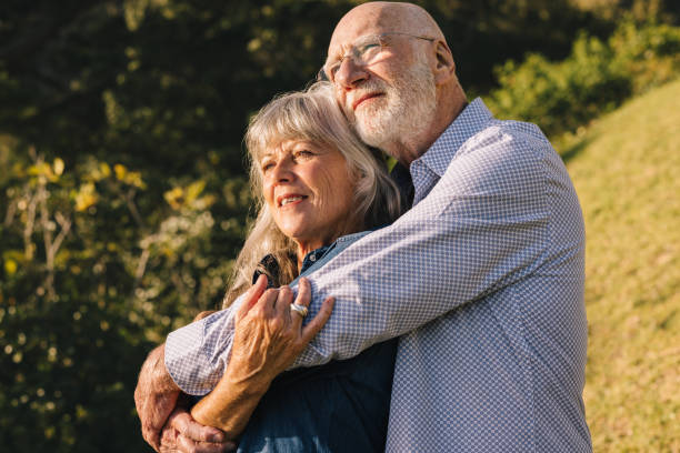istock Romantic senior couple embracing each other in a park 1369301807