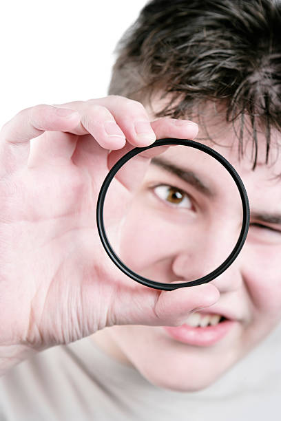 XL teen boy with magnifying glass teen boy in close-up looking through magnifying glass determination focus the bigger picture human hand stock pictures, royalty-free photos & images