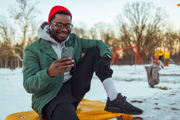 istock African american man sitting outdoors before his training. He is holding mobile phone and looking at it. 1369306382