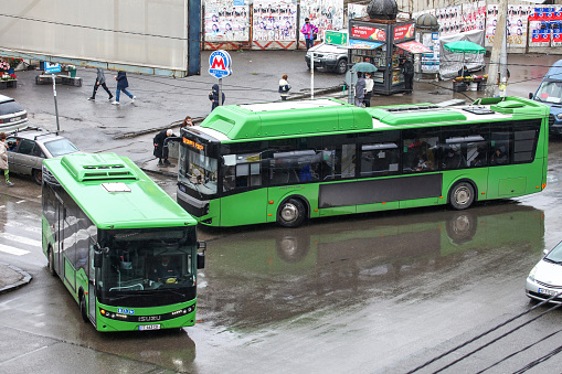 Tbilisi, Georgia - October 5, 2021: Green urban buses Anadolu Isuzu Novo Citi Life and BMC Procity 12 LF CNG in a city street.