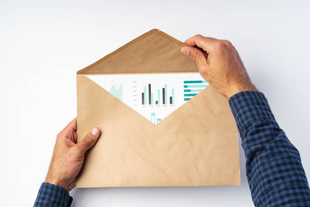 istock Male hands opening craft paper envelope above white surface 1369307121