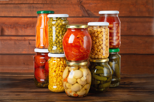 Jars with pickled vegetables and beans on wooden background. Preserved food