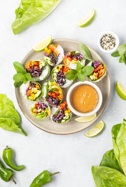 Vegan rainbow-colored spring rolls served with peanut sauce