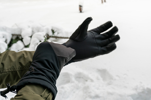 Man putting winter gloves on outside while it’s snowing