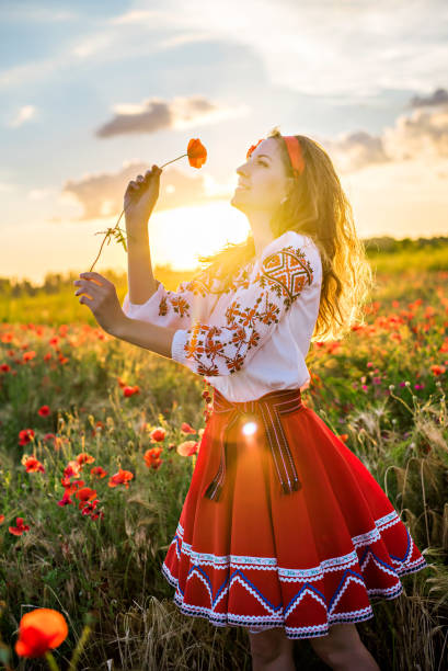 nahaufnahme einer jungen frau auf dem feld, die roten mohn in den händen hält. mädchen in tracht - aboriginal art aborigine rock stock-fotos und bilder