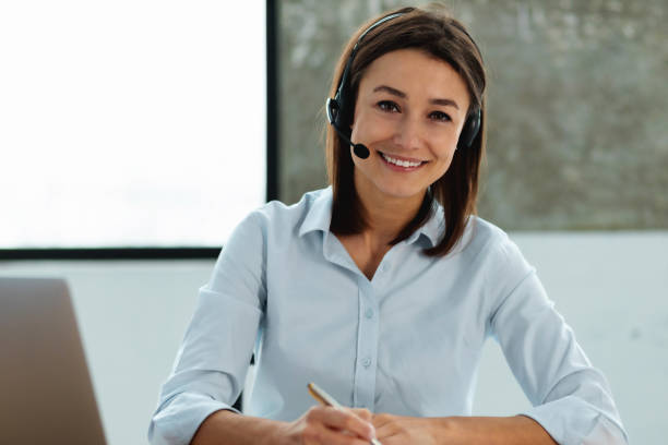 istock Woman customer support phone operator with headset working. Portrait beautiful caucasian young female call center worker looking at the cameras, smiles friendly 1369314879