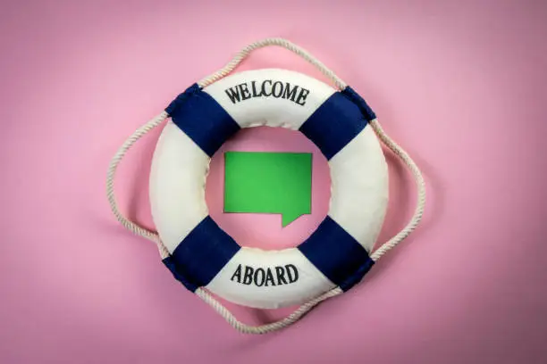 Photo of Miniature lifebuoy with an inscription and a green speech bubble in the center. Copy space