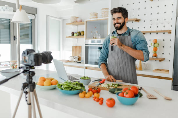istock Young handsome man vlogging in the kitchen 1369318207