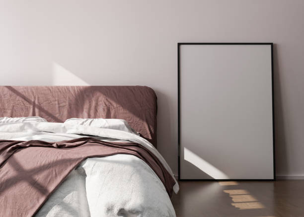 istock Empty vertical picture frame standing on wooden floor in modern bedroom. Mock up interior in minimalist, contemporary style. Free space for picture or poster. Bed, sunlight. 3D rendering. 1369320156