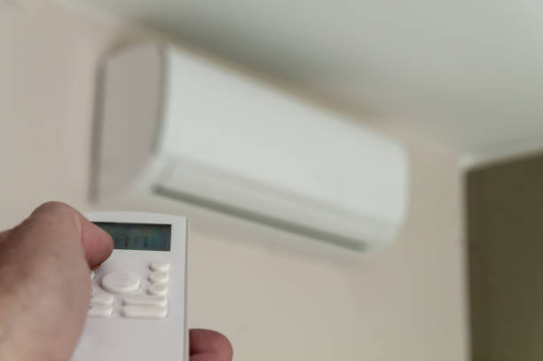 istock a man's hand holds the remote control of a wall-mounted conditioner 1369322143