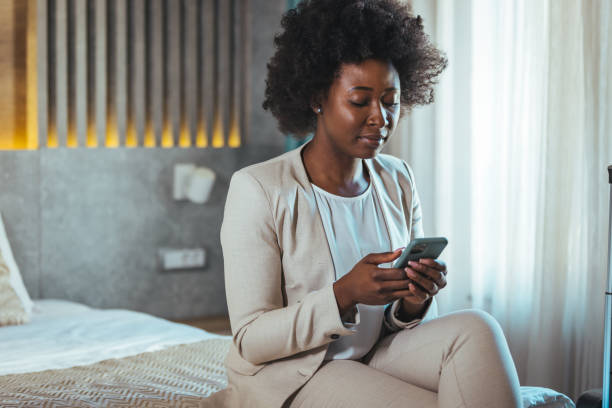 istock Young black businesswoman just arrived at the hotel taking a rest from a trip, using a smartphone. 1369323672