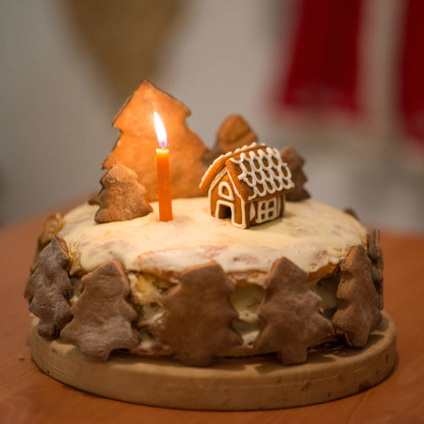 Large tiered Christmas cake decorated with gingerbread cookies and a house on top. christmas cake with a house and trees