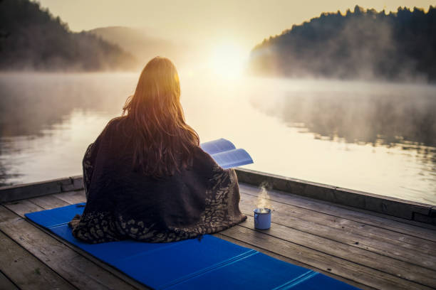 Woman relaxing with book and coffee on sunrise. stock photo