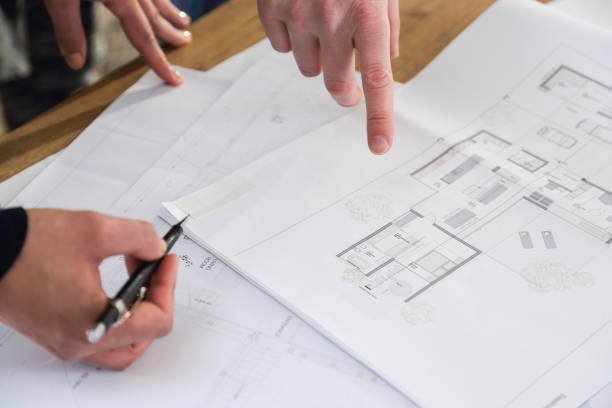 istock Man and woman looking at plans at construction site closeup 1369327035
