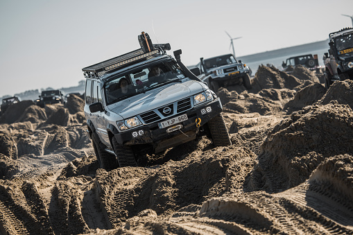 Rockanje, Netherlands -  Sunday October 24th, 2021: Off road 4x4 vehicles driving through man made sand trenches on a public beach on a sunny Sunday morning in the autumn of 2021 in Rockanje, the Netherlands