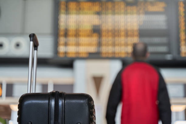Security against robbery. Young man walking away from unattended suitcase to look at panel at airport