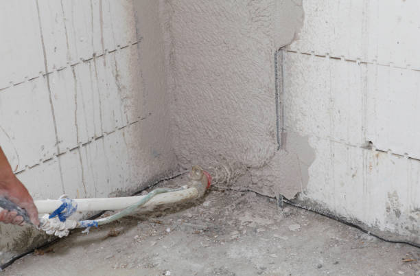 istock Applying plaster, stucco on a wall from insulating concrete forms ICF with a stucco sprayer, stucco texture hopper in the corner, problem area of a house. 1369329910