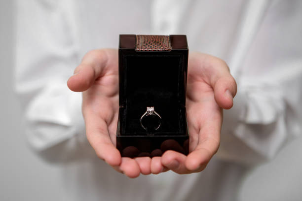 istock A young man holds in his hands a jewelry box with a diamond ring inside 1369330965