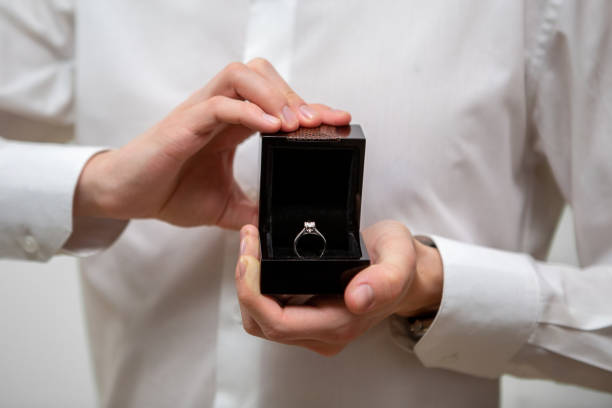 istock A young man holds in his hands a jewelry box with a diamond ring inside 1369331138