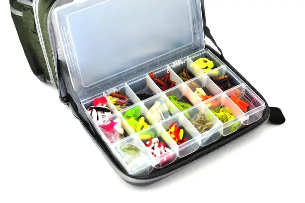 Photo of A box with a variety of silicone baits lies in a fishing bag, white background close-up