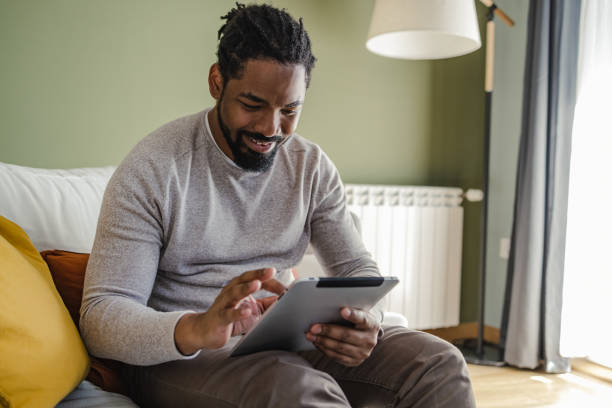 istock Young African-American man using digital tablet at home 1369335011