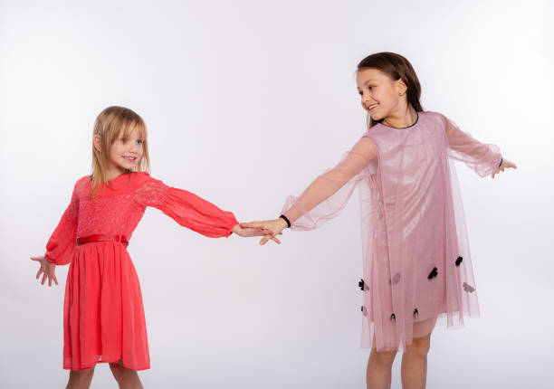 игривые дети, веселая концепция. портрет двух милых девочек 6-8 лет в розовом платье и танцующих изолированно на белом фоне. день матери, семь - female 8 9 years child excitement стоковые фото и изображения