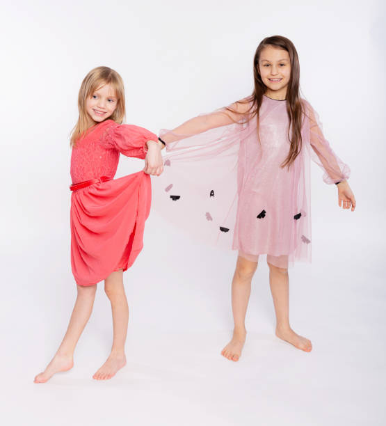 niños juguetones, concepto de tiempo de diversión. retrato de dos lindas niñas de 6 a 8 años con vestido rosa y bailando aisladas sobre fondo blanco. día de la madre, familia amorosa, concepto de infancia de paternidad - 8 9 years studio shot friendship sibling fotografías e imágenes de stock