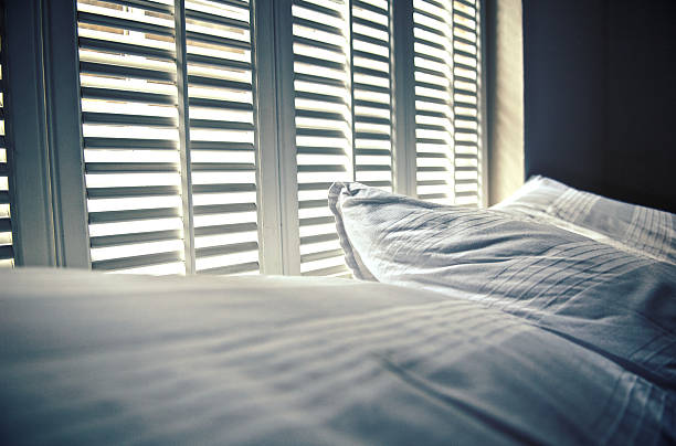 White linen against white shutters with white light behind stock photo