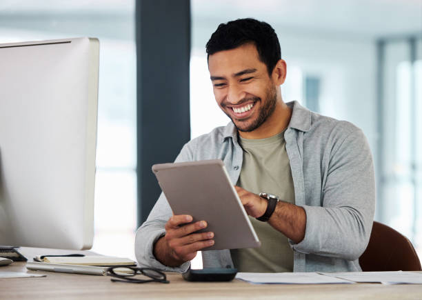 scatto di un giovane uomo d'affari che usa il suo tablet digitale - businessman men business person smiling foto e immagini stock