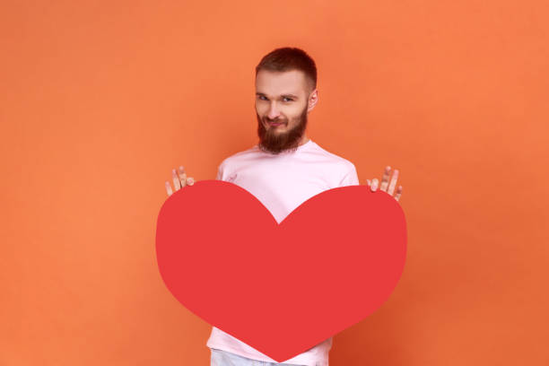 istock Positive optimistic man holding big red heart, expressing positive romantic emotions. 1369339276