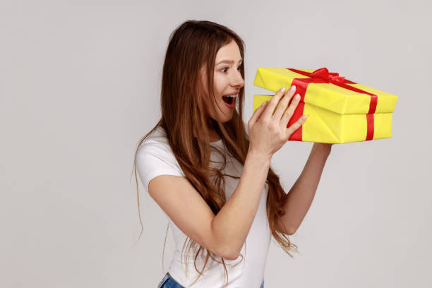 istock Woman unboxing present box, looking inside with surprised facial expression, birthday gift. 1369340542