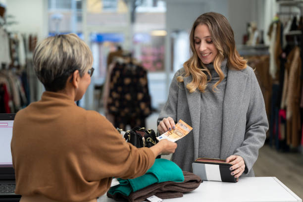 jovem loira pagando em dinheiro na loja de roupas com uma conta de 50 euros - clothing store sales clerk usa clothing - fotografias e filmes do acervo