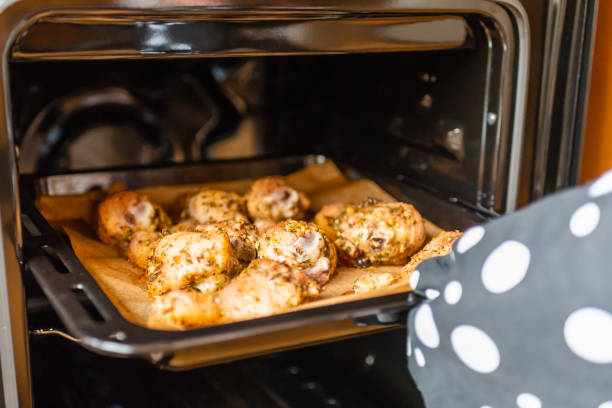 istock Woman's hand pulls out baked chicken legs from the oven.Soft focus,selective focus. 1369345447