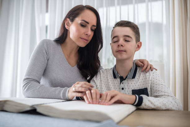 woman helps visually impaired boy in dark glasses reads from a book in braille. boy to read a book in braille. - dot gain fotos imagens e fotografias de stock