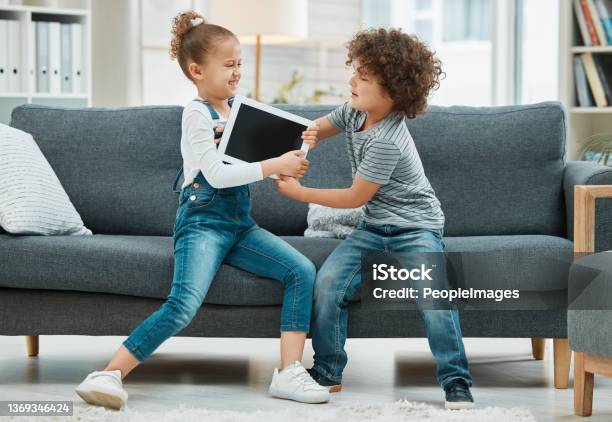 Shot Of Two Siblings Fighting In A Game Of Tug Of War Over Their Digital Tablet Stock Photo - Download Image Now