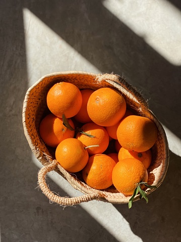 Fondo con luces y sombras y cesta de paja llena de naranjas photo
