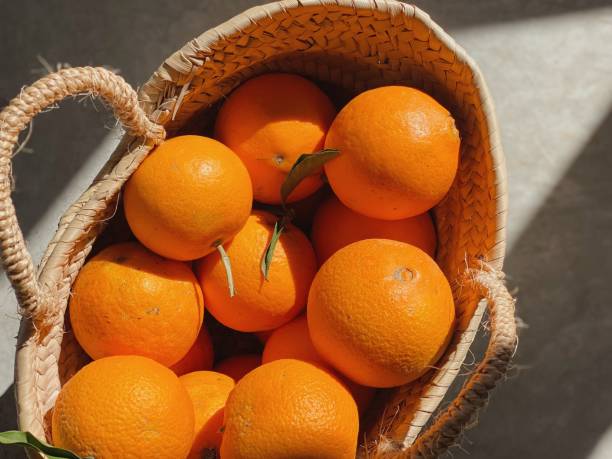 istock Background with lights and shadows and straw basket full of oranges 1369349219