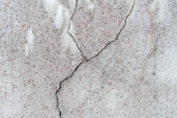 istock Cracked concrete wall gray cement surface background.cracked grey stone wall in winter.close-up. 1369349412