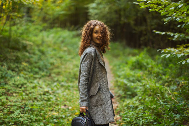 Redhead curly beautiful girl in coat in autumn forest. Autumn break. Pretty woman enjoying autumn vacation. Visit local attractions. Girl laughing in nature. Feel happiness. Charming smile. Happy lady pelirroja hermosa chica rizada con abrigo en el bosque de otoño. vacaciones de otoño. mujer bonita disfrutando de las vacaciones de otoño. visite las atracciones locales. chica riendo en la naturaleza. siente felicidad. sonrisa encantadora. feliz dama