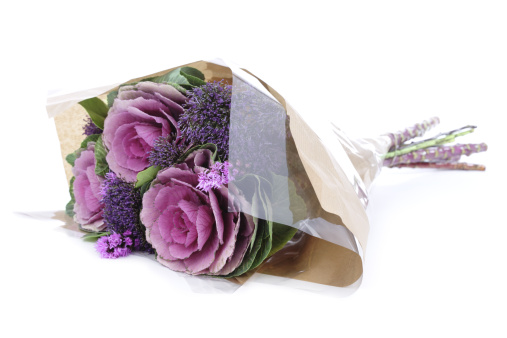 Seasonal bouquet for autumn and winter containing ornamental cabbages and liatris. Wrapped in cellophane and paper, isolated on white