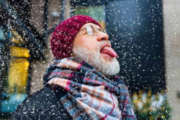 happy good looking mature man sticking out his tongue catches snowflakes in city town happy good looking mature man sticking out his tongue catches snowflakes in city town. town of hope stock pictures, royalty-free photos & images