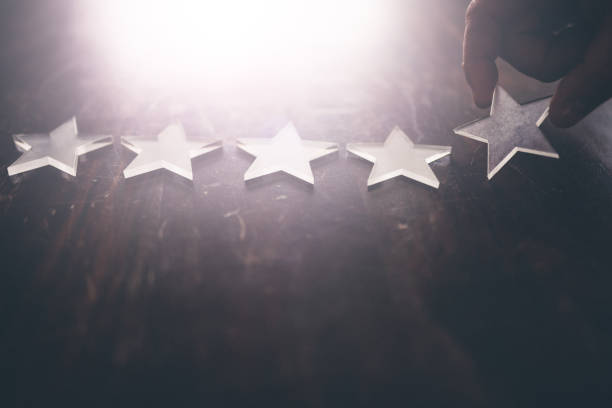 istock Hand arranging 5 stars on a wood desk. 1369353940