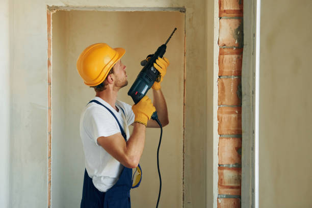 istock Holding electric drill in hands. Young man working in uniform at construction at daytime 1369354917
