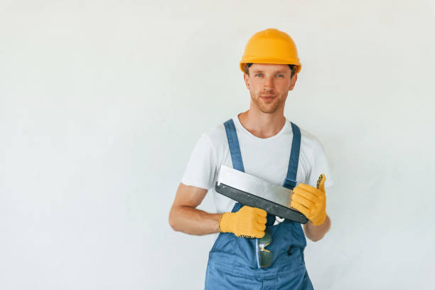 istock Standing near white wall. Young man working in uniform at construction at daytime 1369355473