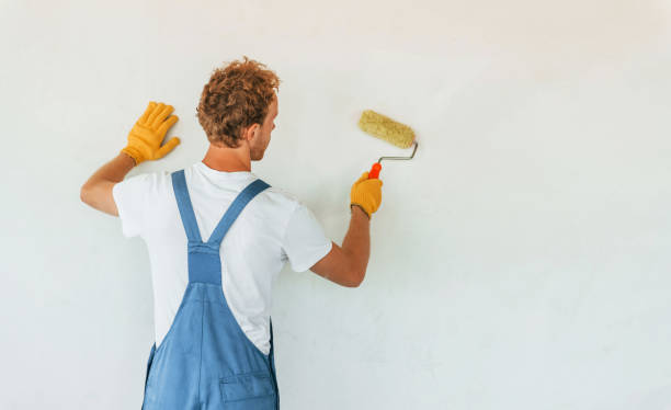 istock Clean walls. Young man working in uniform at construction at daytime 1369355816