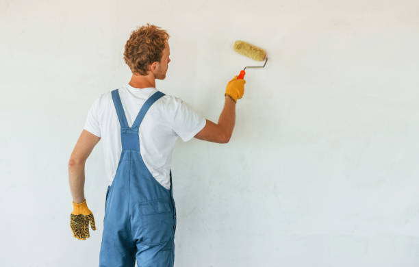 istock Clean walls. Young man working in uniform at construction at daytime 1369355868