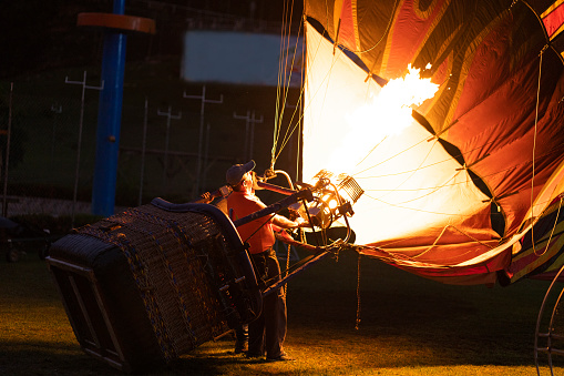 Hot flame from a gas burner light up inside of a hot air balloon at summer evening.