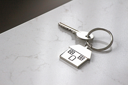 A single house key on a keyring - homeowner, first home, rental, buying/selling themes.